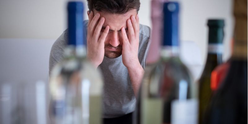 upset man with several bottles of alcoholic beverages