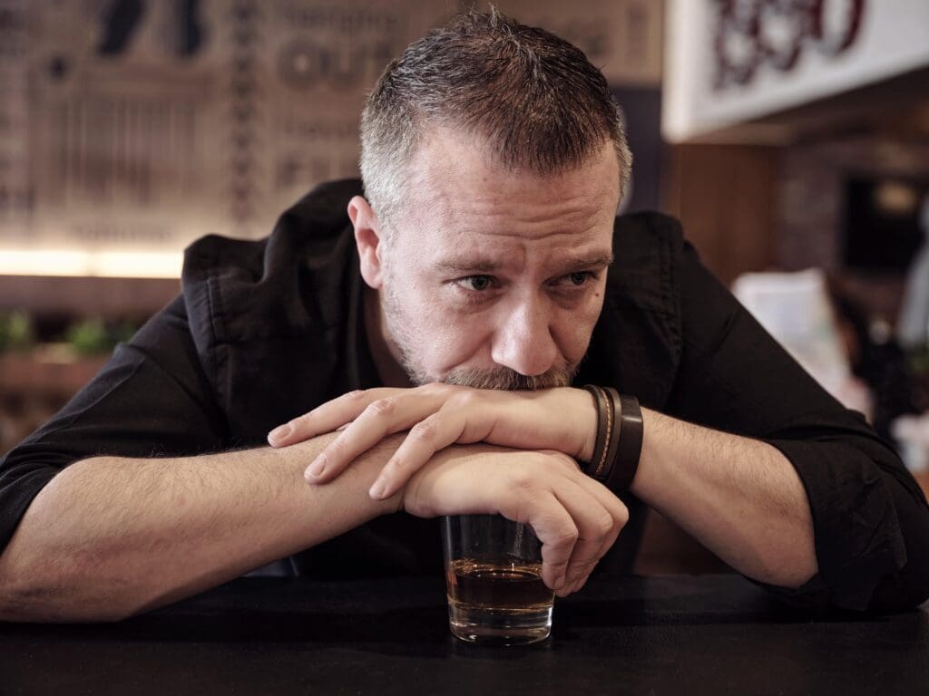 man covering his drink wonders if he is an alcoholic