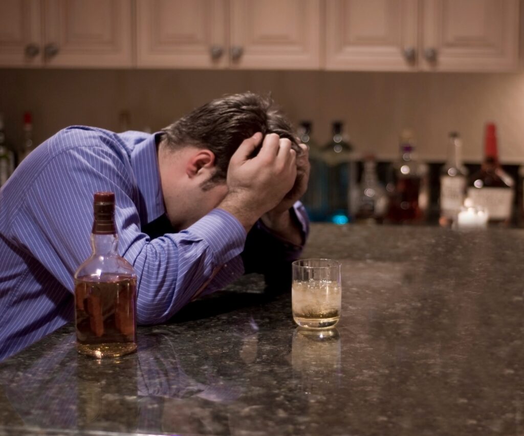man with an alcohol addiction drinking in his kitchen