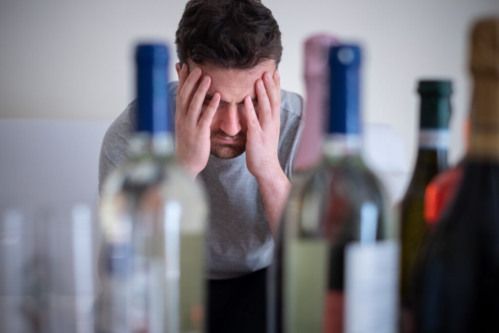upset man with several bottles of alcoholic beverages
