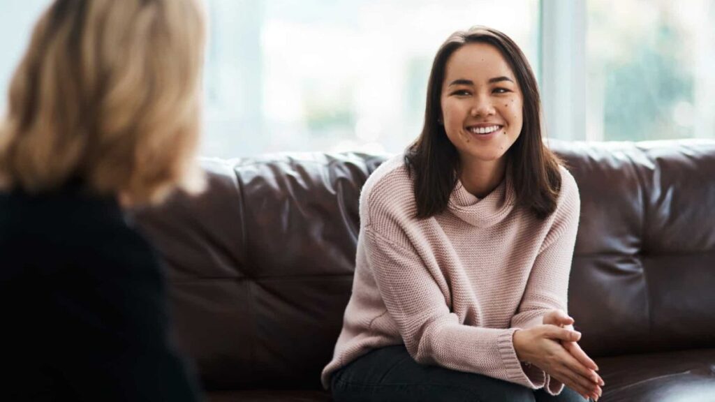 Therapist talking to young client about holistic mental health treatment.