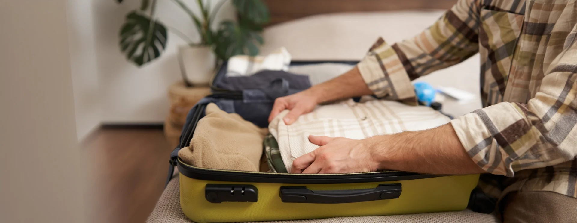 Person packing a suitcase while preparing to travel for addiction treatment